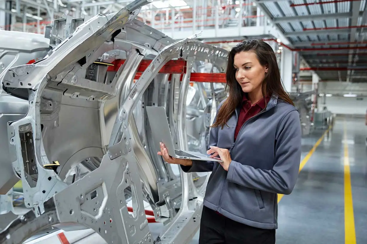 A woman in an automotive plant, checking car parts before they are shipped